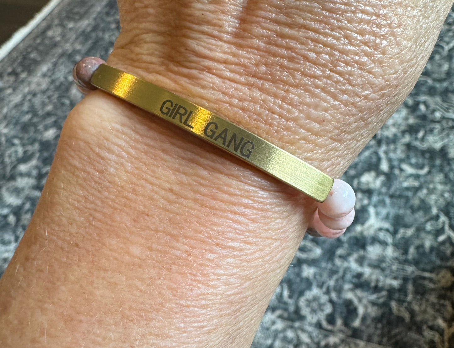 Gold bracelet complimenting pink and multicolor beads with "GIRL GANG" engraved on gold.